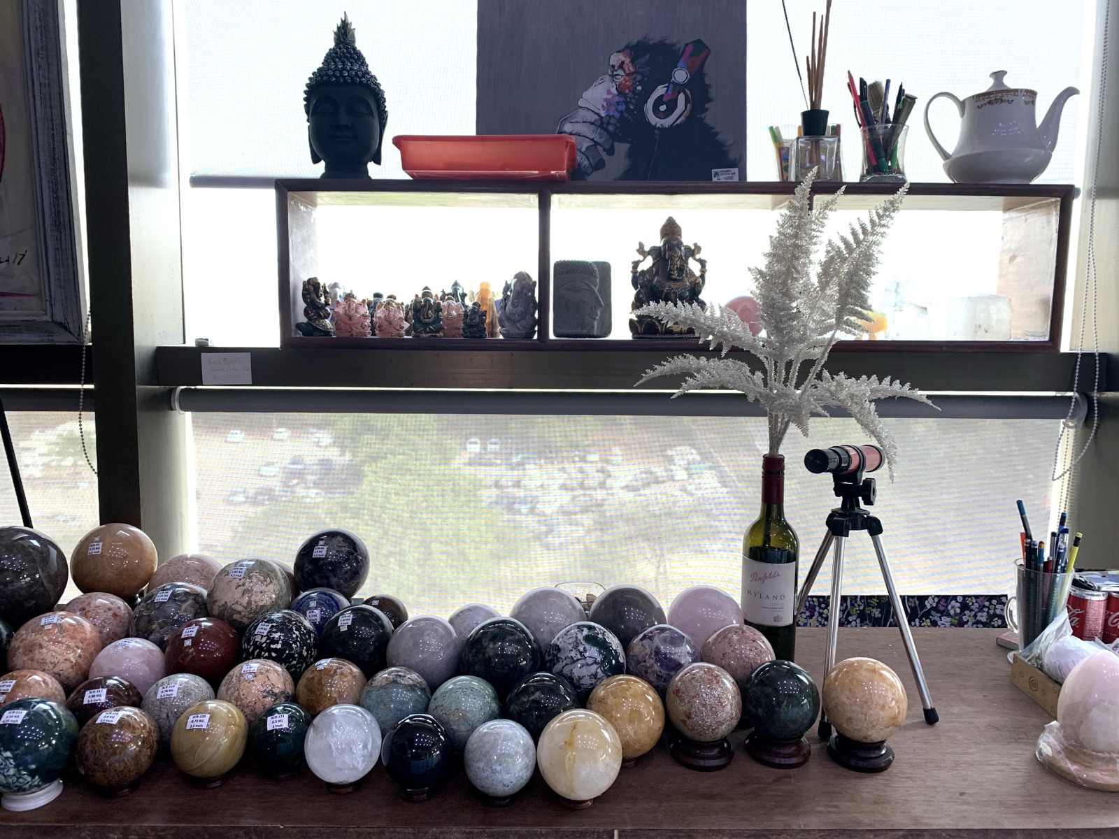 The gallery studio with buddha, ganesha shelf and rows of polished gemstone spheres